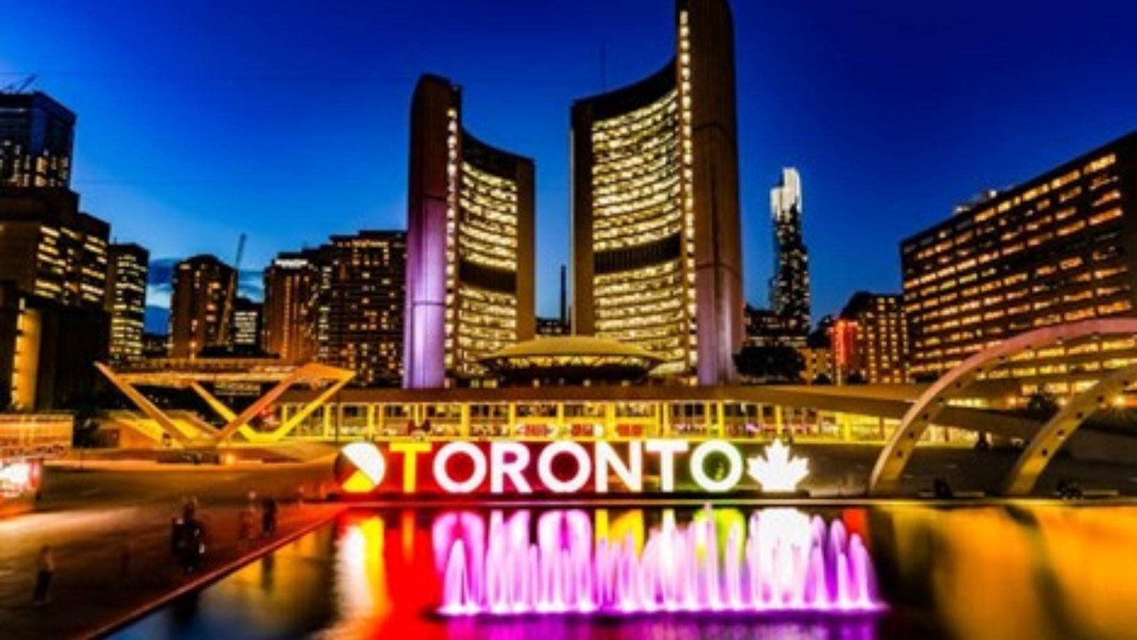 Buildings, skyscrapers, and a neon Toronto sign at nighttime.